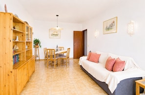 Ein Wohnzimmer mit einer Holzhülle, einem Esstisch mit Stühlen, einer Couch mit Kissen und einer Hängeleuchte.