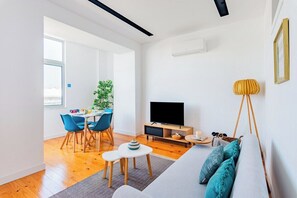 Een moderne woonkamer met televisie, bank en eethoek.