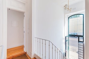 A staircase with a metal railing, a wooden floor, and a view of the street through a glass door. - Urban Haven: 2BR Modern Retreat (Lisbon)
