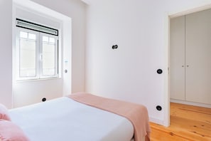 A bedroom with a bed, a window, a door, and a wardrobe. - Urban Haven: 2BR Modern Retreat (Lisbon)