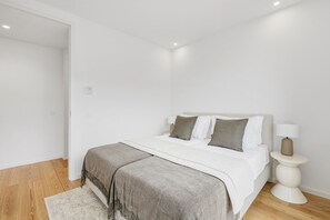 Ein Schlafzimmer mit einem Bett, Nachttischen, einem Teppich und einer Tür.