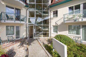Ein mehrstöckiges Gebäude mit Balkonen, einer zentralen Treppe und einem gepflasterten Weg.