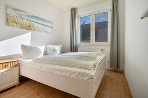 A bedroom with a bed, a window, a radiator, and a painting on the wall. - Apartment 'Diana' with Terrace and 300 m from the Beach (Zempin)