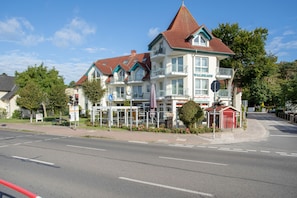 Ein mehrstöckiges Hotel mit rotem Ziegeldach, Balkonen und Außenbereichen zum Sitzen.