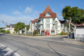 Ein Gebäude mit rotem Dach und mehreren Balkonen, mit Hinweisen auf ein Restaurant, eine Pizzeria und eine Bar.