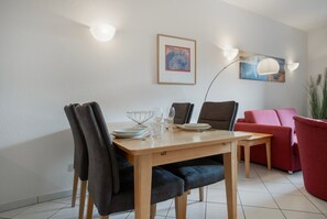 Ein Essbereich mit Tisch, Stühlen und einem roten Sofa.