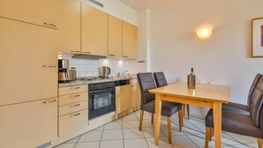 Een moderne keuken met een eethoek, inclusief een fornuis, oven en een tafel met stoelen.