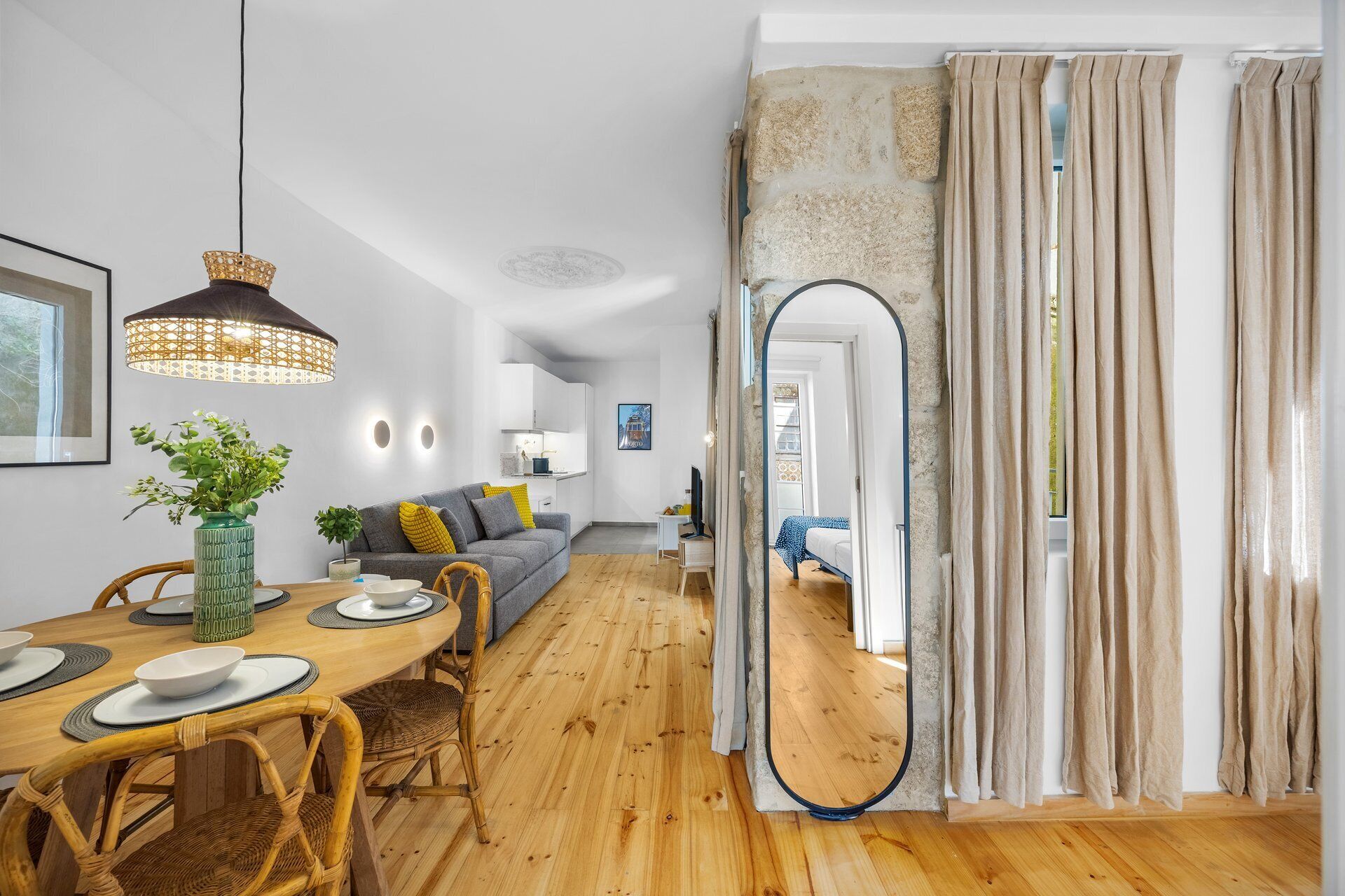 Een moderne woonkamer met een eethoek, een bank, een salontafel en een grote spiegel.
