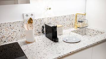 Uma cozinha com cafeteira, porta-xícaras e moedor de café no balcão.