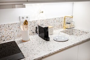 Uma cozinha com cafeteira, porta-xícaras e moedor de café no balcão.