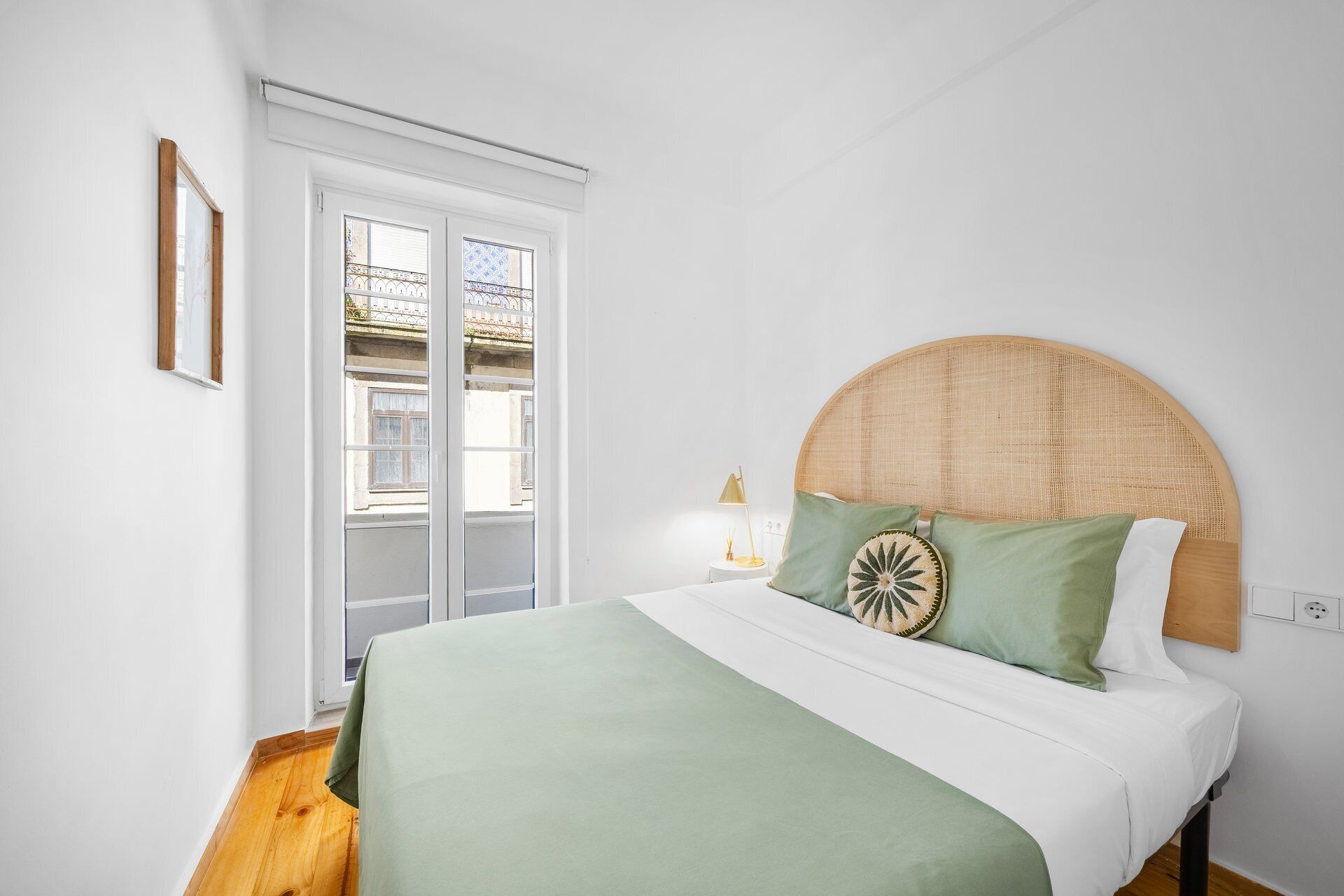 Une chambre à coucher avec un lit, une table de chevet avec une lampe, une fenêtre et une porte.