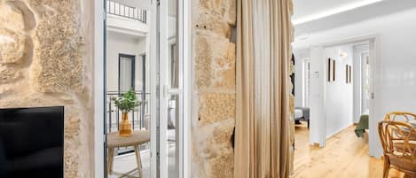 A room with a stone wall, a glass door, a wicker chair, and a flat-screen TV.