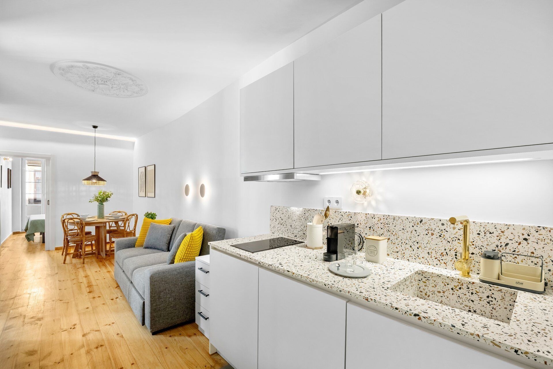 Une cuisine moderne avec des meubles blancs, un plan de travail à motifs et un évier encastré.
