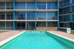 Un edificio de varios pisos con una piscina delantera.