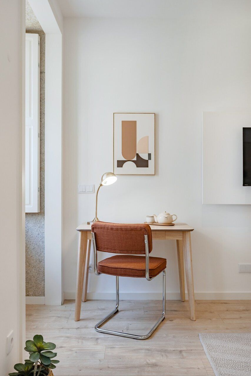 Un espace de bureau moderne comprenant un bureau, une chaise, une lampe et une œuvre d’art abstraite encadrée.