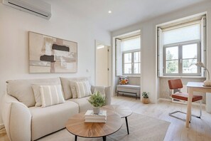 A modern living room with a sofa, coffee table, and a painting on the wall. - The Soft Escape @ BoaVista Flats (Porto)