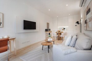 Ein modernes Wohnzimmer mit Flachbildfernseher, einer Couch, einem Couchtisch und einem Essbereich mit Stühlen und einem Tisch.