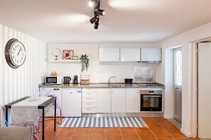 A compact kitchen with white cabinets, a microwave, a sink, and a stove. - Gaia Elegant Retreat I (Canidelo)