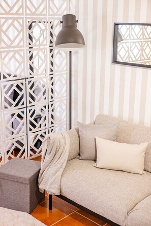A living room with a sofa, ottoman, and a floor lamp. - Gaia Elegant Retreat I (Canidelo)