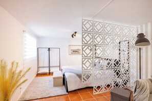 Een slaapkamer met een bed, nachtkastje, lamp en decoratief roomdivider.