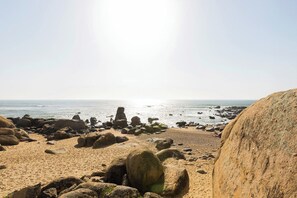 Een strand met grote rotsen en een helder uitzicht over de oceaan.