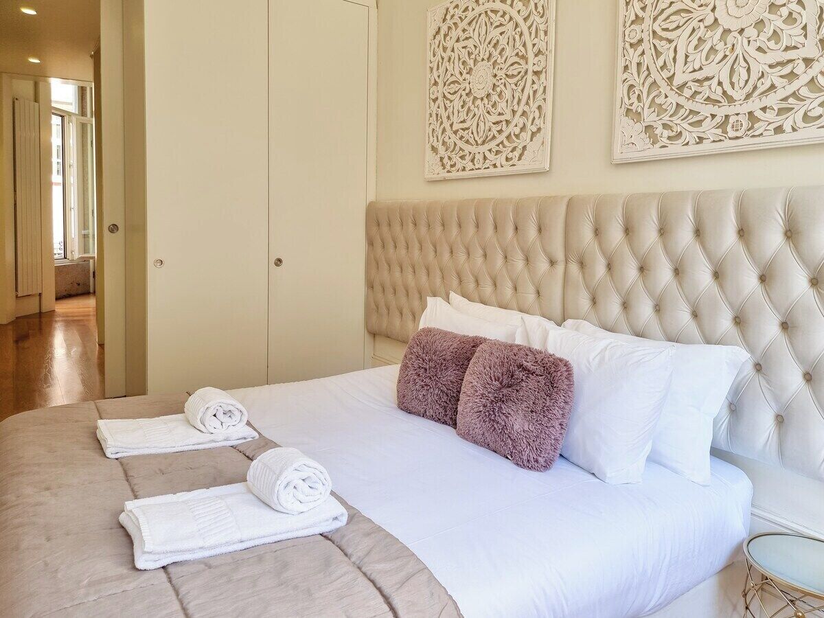 A hotel room with a large bed, a tufted headboard, decorative wall panels, and neatly folded towels on the bed.