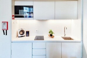 A compact kitchen with a built-in microwave, a sink, and a small potted plant. - Inspiring City Center 1 BR Apartment with a View (Porto)