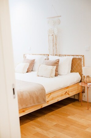 Ein Bett mit Holzrahmen, weißer Bettwäsche und mehreren Kissen.