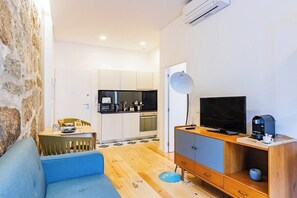 Ein modernes Wohnzimmer mit einer Couch, einem Fernseher und einer Kaffeemaschine.