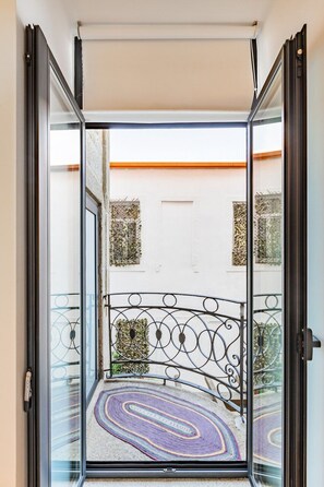 A glass door leading to a balcony with a metal railing and a patterned rug. - Netto City Vibes (Porto)