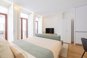 Ein modernes Schlafzimmer mit Bett, Fernseher und Kleiderschrank.