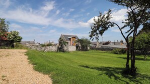A rural house with a stone wall, a grassy lawn, and a clear sky. - 6 Hill Street (Banff)