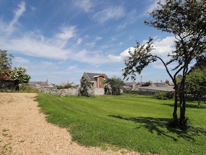 Ein ländliches Haus mit Steinmauer, Rasenfläche und blauem Himmel.