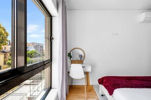 A bedroom with a large window, a desk with a chair, a bed, and a mirror. - CharmINN Paraíso | Porto | AC (Porto)