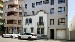 A multi-story building with a parking sign, two parked cars, and a garage door. - CharmINN Paraíso | Porto | AC (Porto)