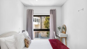 A bedroom with a bed, a desk, and a view of the outside. - CharmINN Paraíso | Porto | AC (Porto)