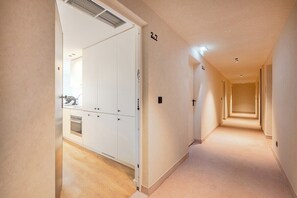 A hallway with a wooden floor, white walls, and a door leading to a bathroom. - Balcony Garden Views @ Terracotta Collection (Porto)