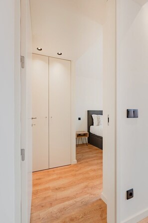 A hallway leading to a bedroom with a bed, a bedside table, and a wardrobe. - Balcony Garden Views @ Terracotta Collection (Porto)
