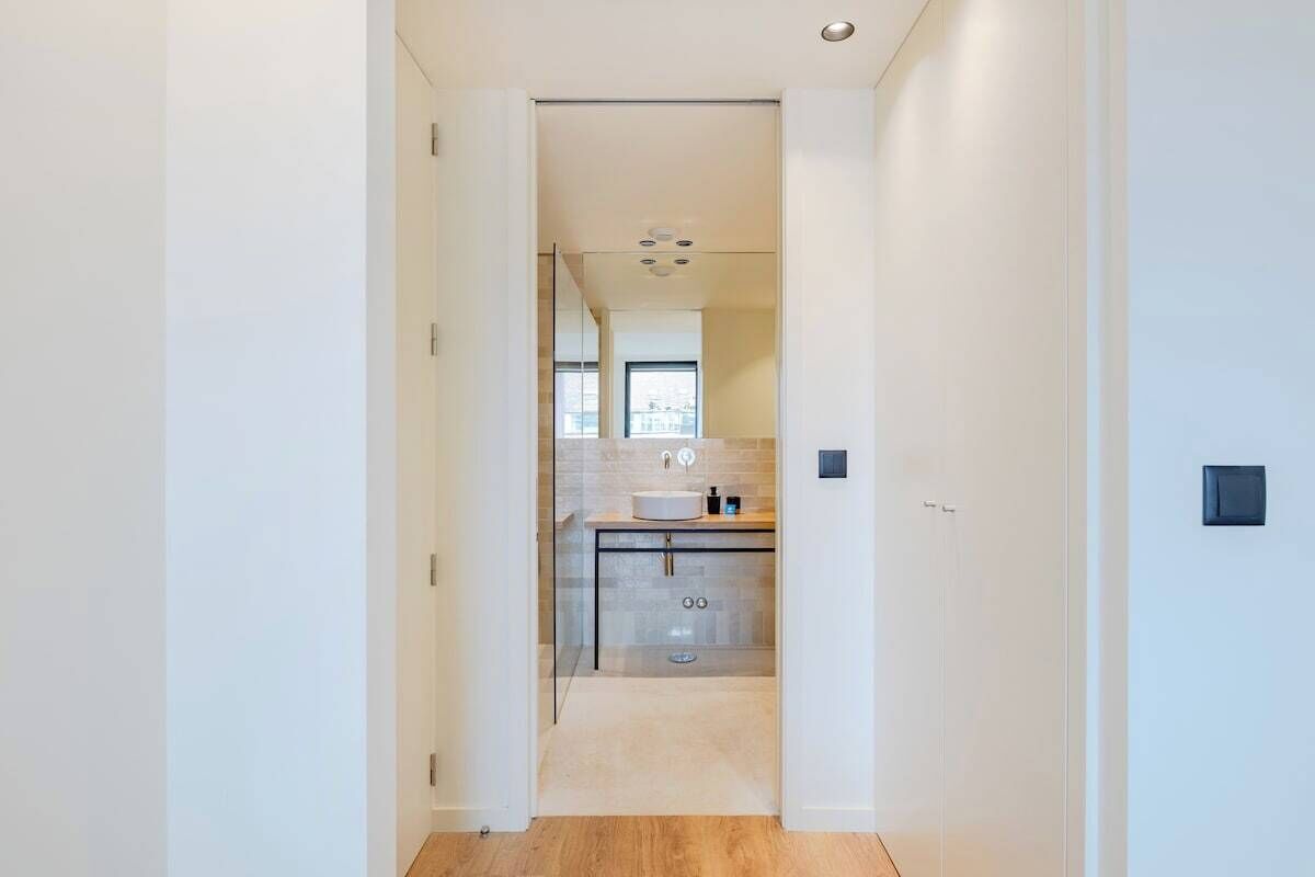 Een moderne badkamer met een douchecabine van glas, een wastafel en een spiegel.