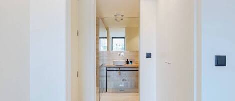 Un baño moderno con cabina de ducha de vidrio, un lavabo y un espejo.