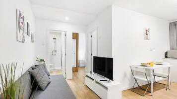 Un salon moderne avec un canapé, un téléviseur et un coin repas.