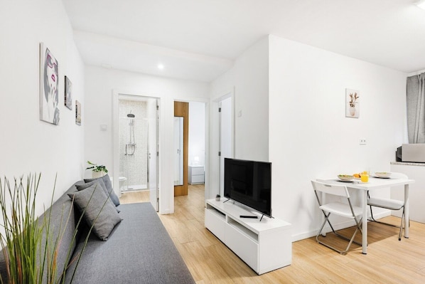 Un salon moderne avec un canapé, un téléviseur et un coin repas.