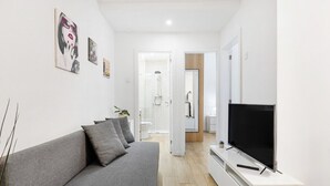 A modern living room with a grey sofa, a flat-screen TV, and artwork on the walls. - Smart Stay in Gaia | Cozy & Work-Ready (Vila Nova de Gaia)
