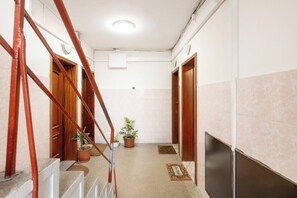 A hallway with a staircase, potted plants, a doormat, and a flat-screen TV mounted on the wall. - Smart Stay in Gaia | Cozy & Work-Ready (Vila Nova de Gaia)
