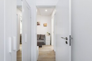 A narrow hallway with a bed, bedside table, and wall art. - Smart Stay in Gaia | Cozy & Work-Ready (Vila Nova de Gaia)