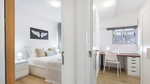 A bedroom with a bed, bedside table, and a window. - Smart Stay in Gaia | Cozy & Work-Ready (Vila Nova de Gaia)