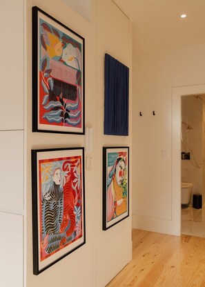 A hallway with framed artworks on the walls, a blue curtain, and a wooden floor. - Oasiys - Your Getaway in Porto (Porto)