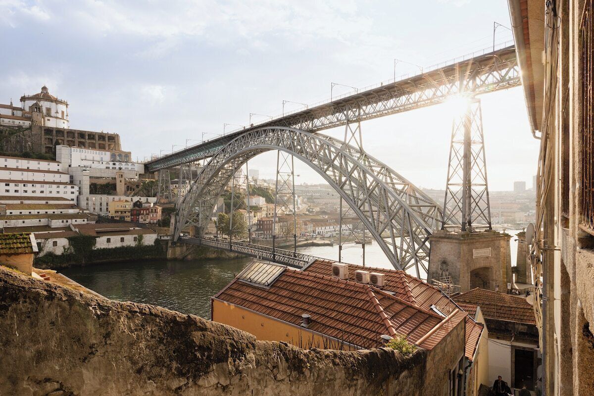 A large steel bridge spanning a river, with buildings on either side.