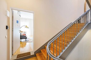 Eine Treppe mit Holzbodenstufen und Metallgeländern, die zu einem Zimmer mit einem Bett und einer Lampe führt.