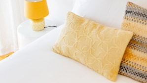 Quarto de hotel com cama, abajur e interruptor na parede.